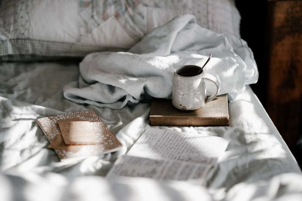 A book and a cup of coffee on a bed