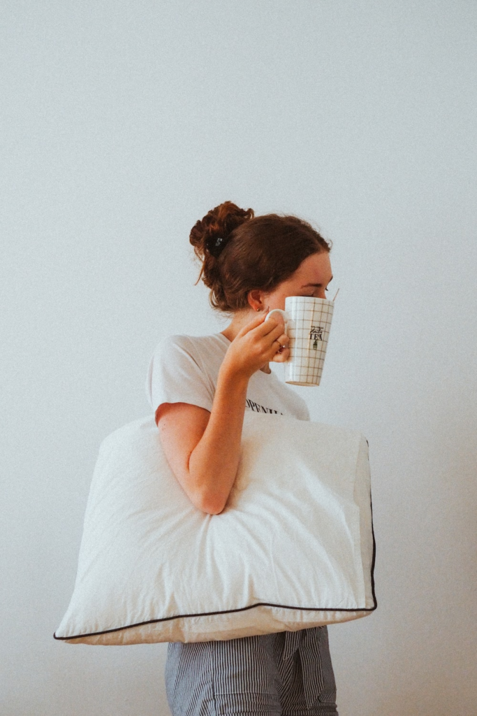 A woman holding a pillow and a mug.
